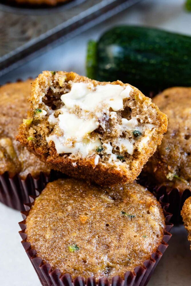 Zucchini muffins with top one split in half and covered in butter
