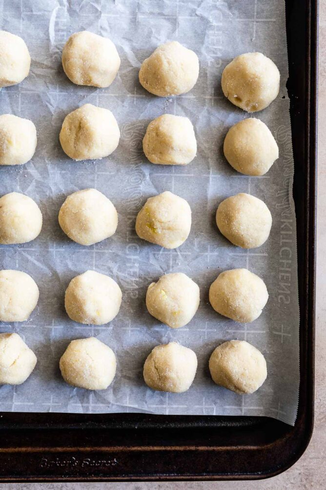 Overhead shot of lemon cookie dough balls on parchment paper before being cooked