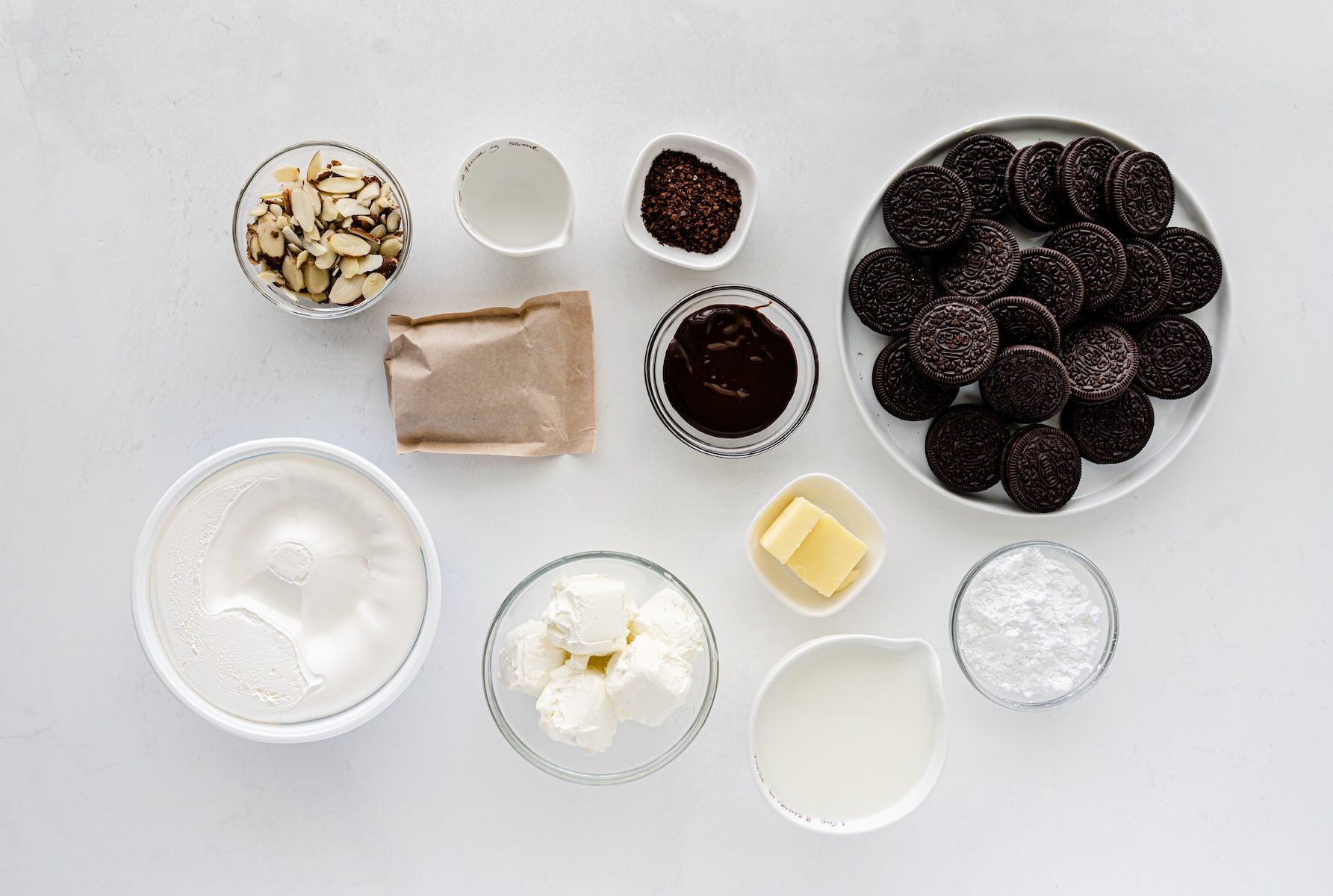 ingredients in mocha mud pie - bowls of Oreos, almonds, whipped cream powdered sugar and butter