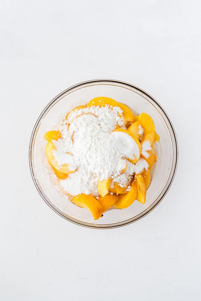 Overhead shot of peaches being mixed with sugar and cornstarch