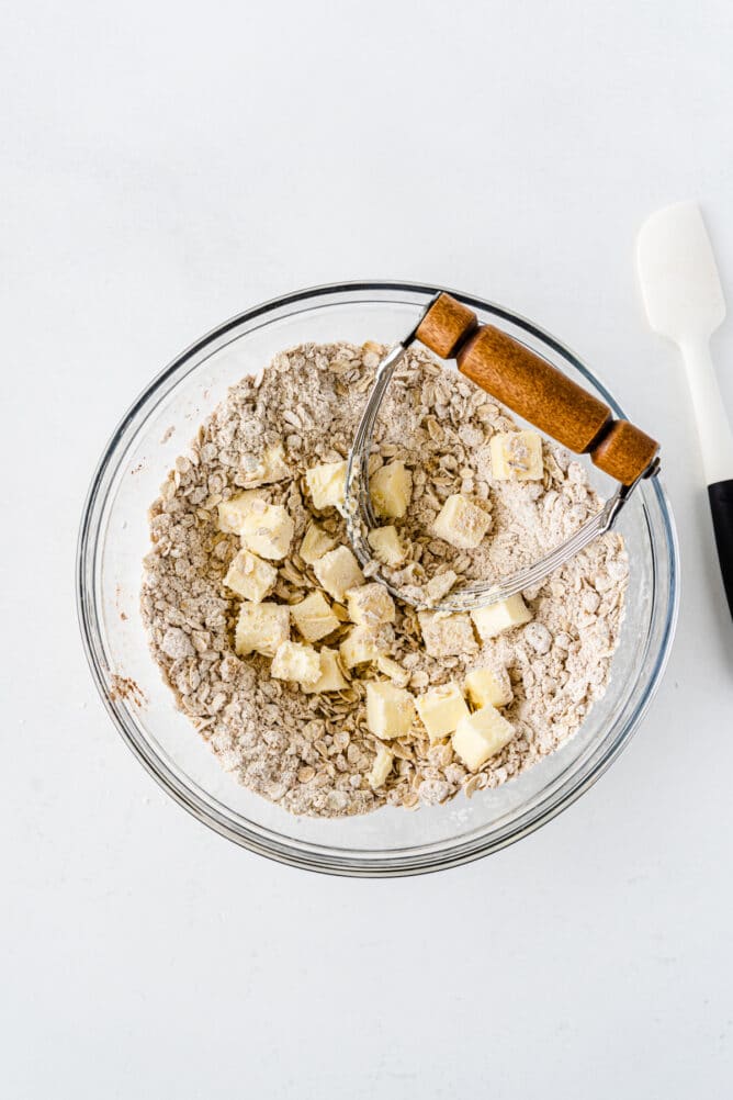 Overhead shot of cubed butter being cut into oat mixture