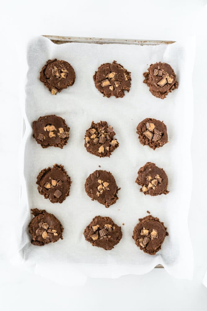 Overhead shot of soft chocolate peanut butter cup cookie dough set on a baking sheet ready to bake