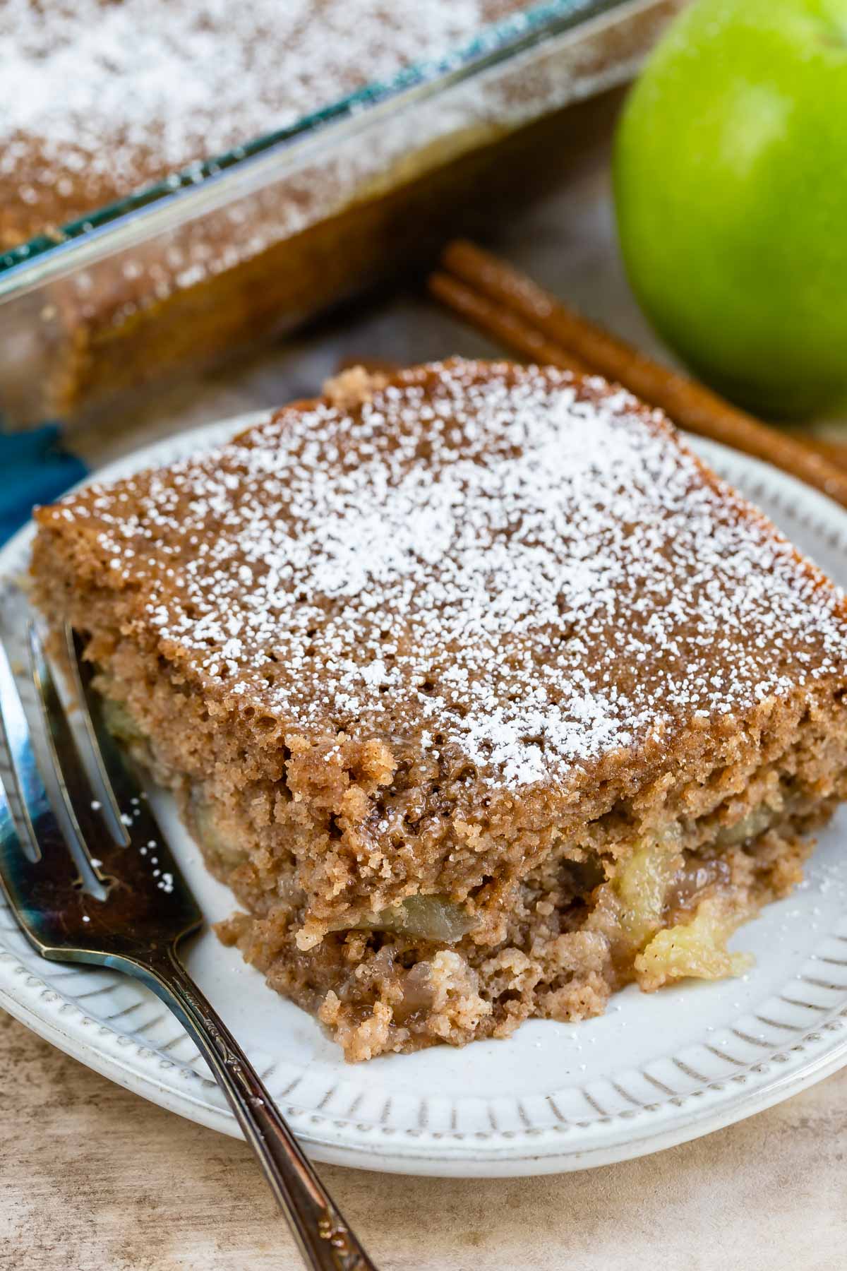 Slice of apple pie cake topped with powdered sugar