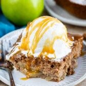 Slice of apple pie cake topped with vanilla ice cream and caramel sauce