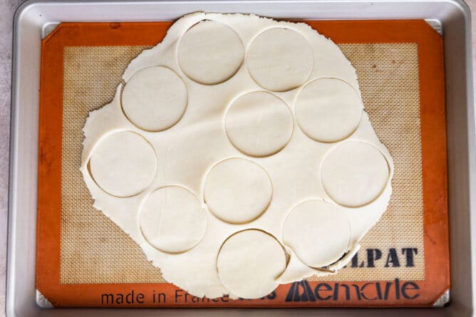 Overhead shot of pie crust circles cut into pie crust on a baking sheet