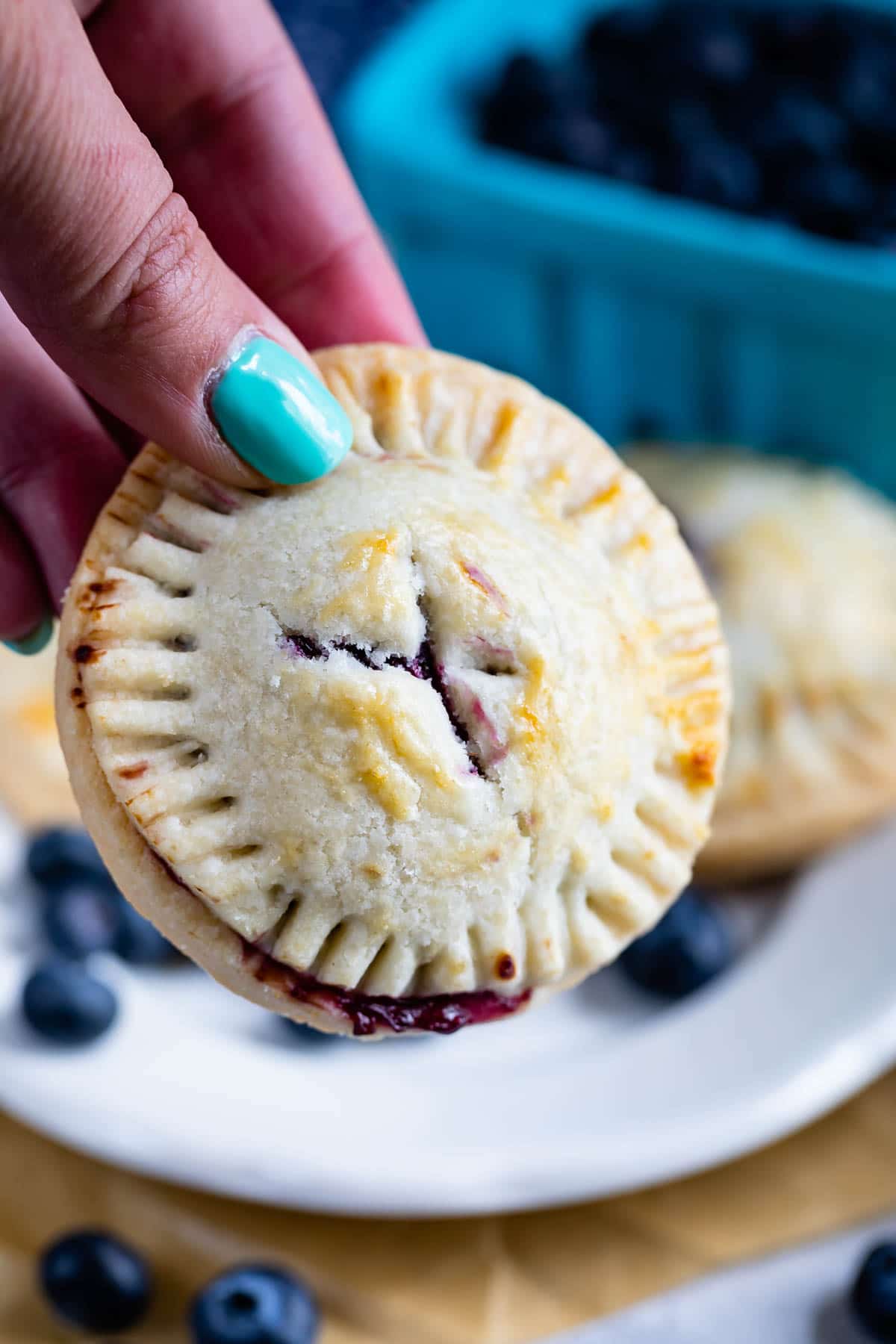 Hand holding a blueberry hand pie up close to the camera