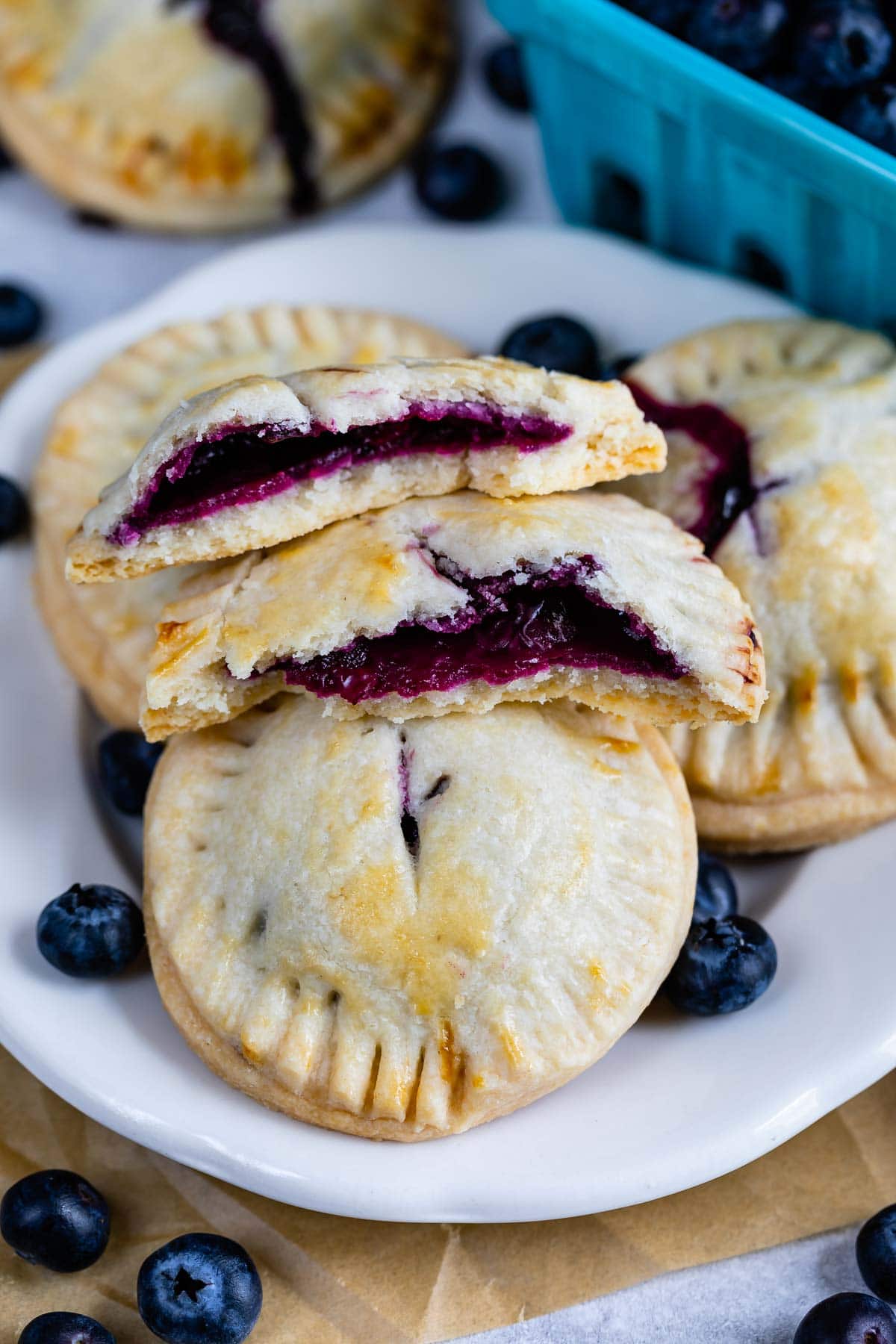 Blueberry hand pies on a plate with one split in half to show blueberry filling