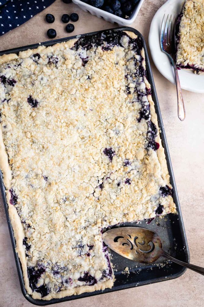 Overhead shot of blueberry slab pie with one corner piece missing
