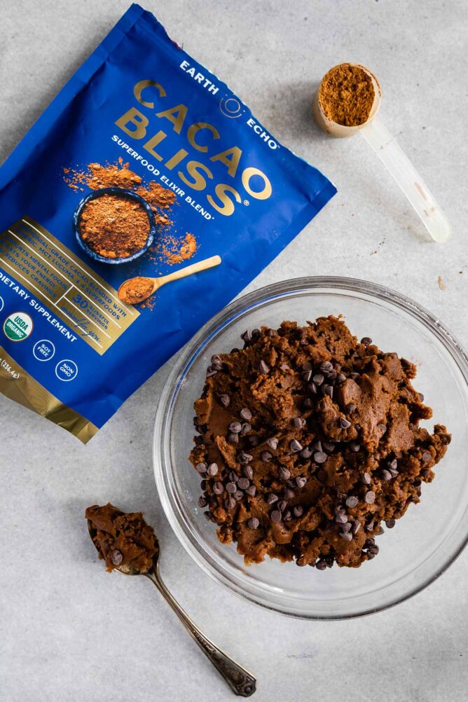 Overhead shot of double chocolate chip cookie dough next to a bag of cacao bliss