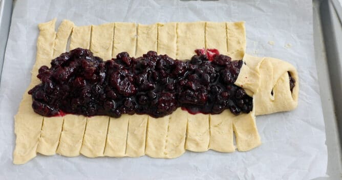 crescent roll dough with filling down the center on cookie sheet