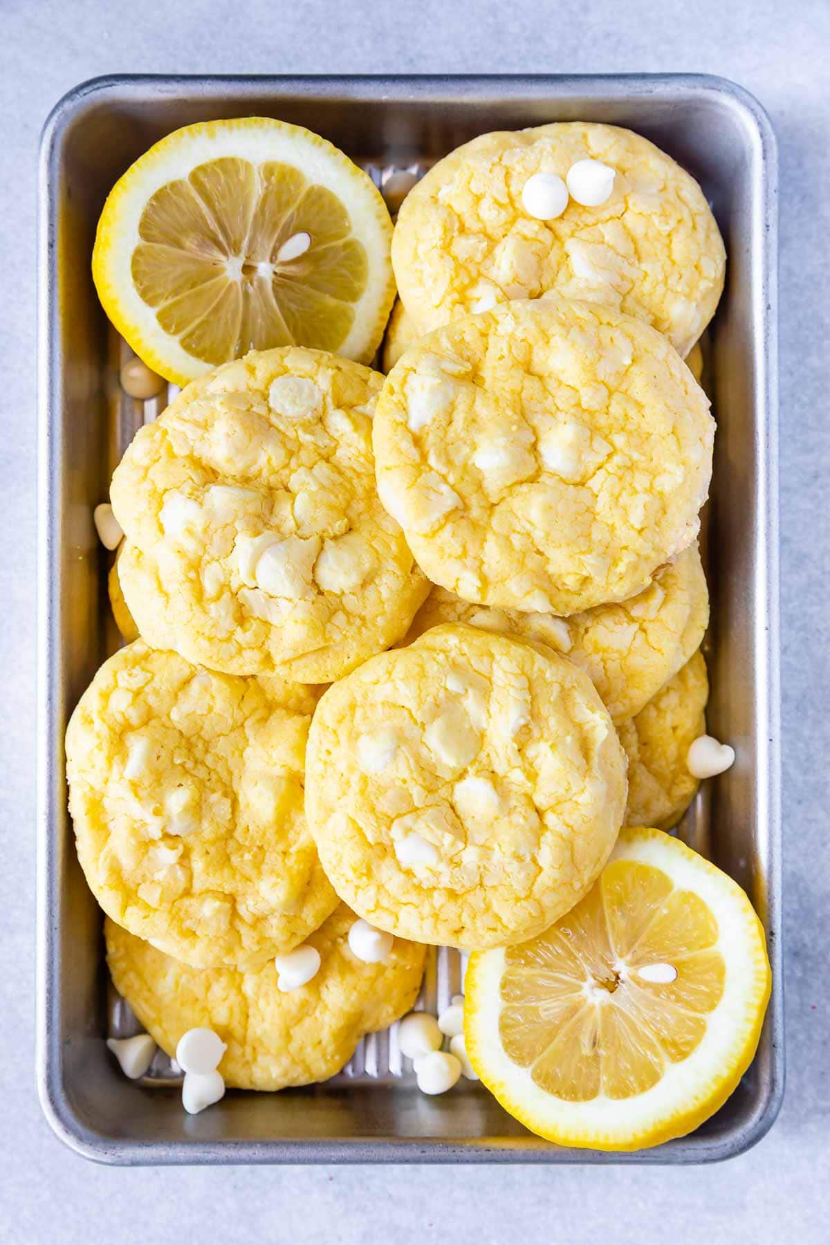 Baking pan full of lemon white chocolate cake mix cookies, white chocolate chips and lemon slices