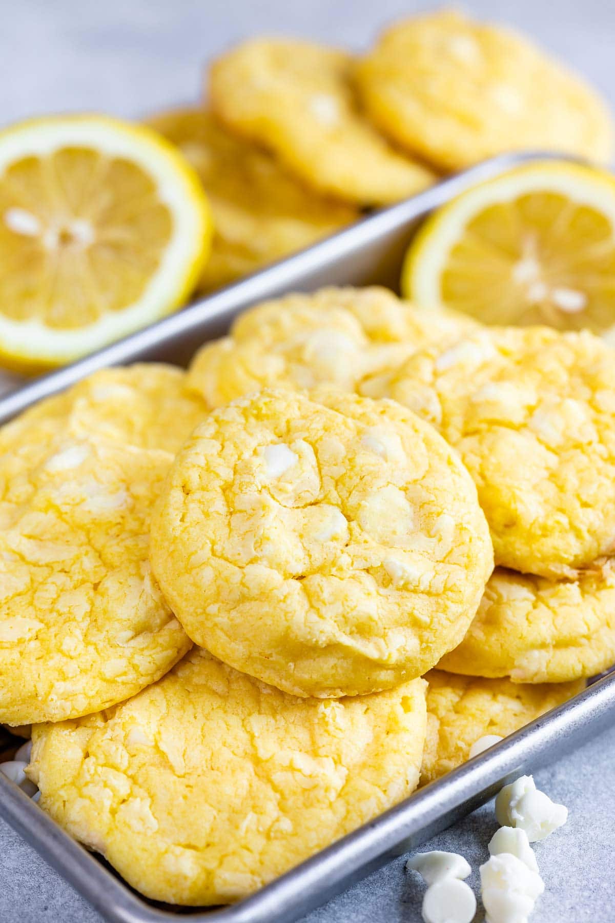 Baking pan full of lemon white chocolate cake mix cookies, white chocolate chips and lemon slices