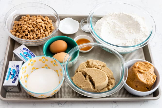 All ingredients needed to make XL bakery style peanut butter cookies measured out on a sheet pan