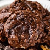 Close up shot of flourless brownie cookies with top cookie split in half with recipe title on top of image