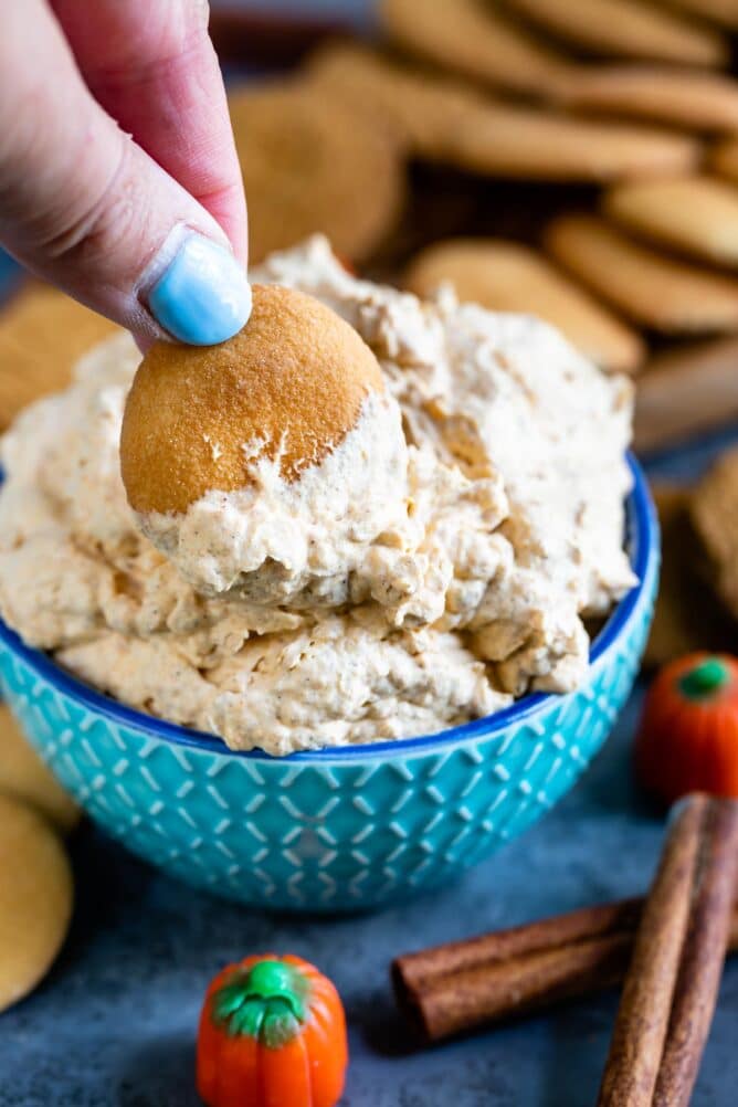 pumpkin fluff in blue bowl with hand dipping vanilla wafer