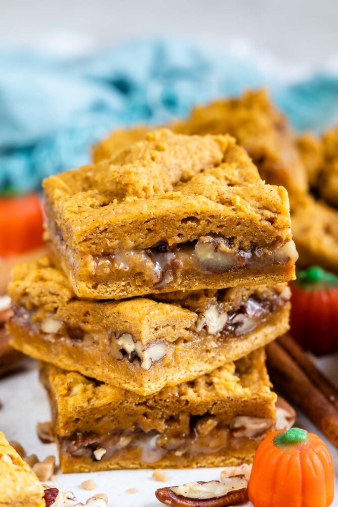 Three pumpkin gooey bars stacked on top of eachother with a pumpkin candy next to them