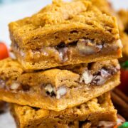 Three pumpkin gooey bars stacked on top of eachother with a pumpkin candy next to them
