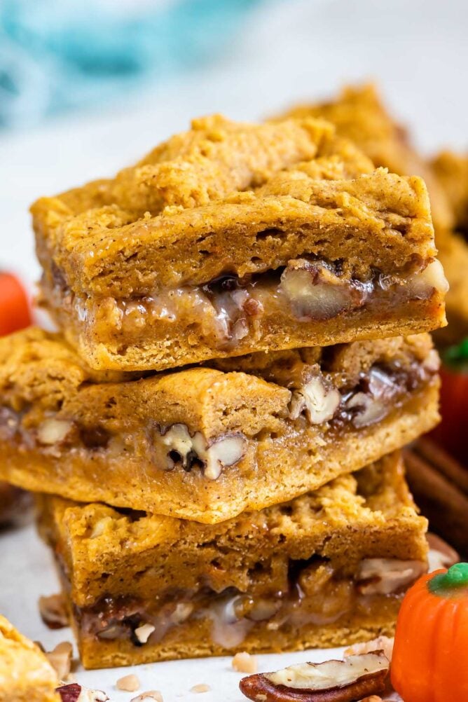 Three pumpkin gooey bars stacked on top of eachother with a pumpkin candy next to them