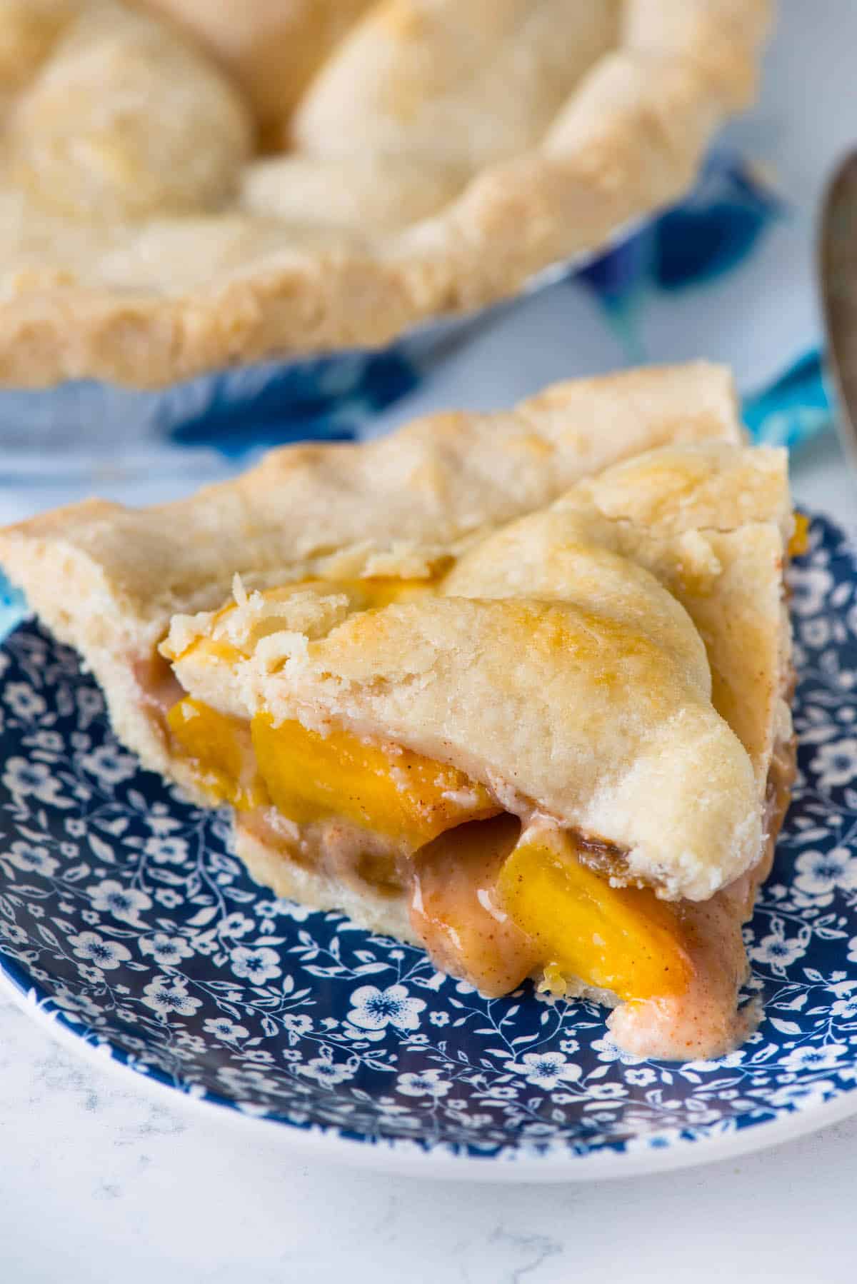 slice of 2 crust peach pie on blue plate