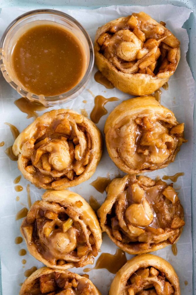 Overhead shot of easy apple cinnamon rolls with caramel frosting in a small dish next to them