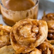 Easy caramel apple cinnamon rolls stacked on eachother with caramel sauce in the background