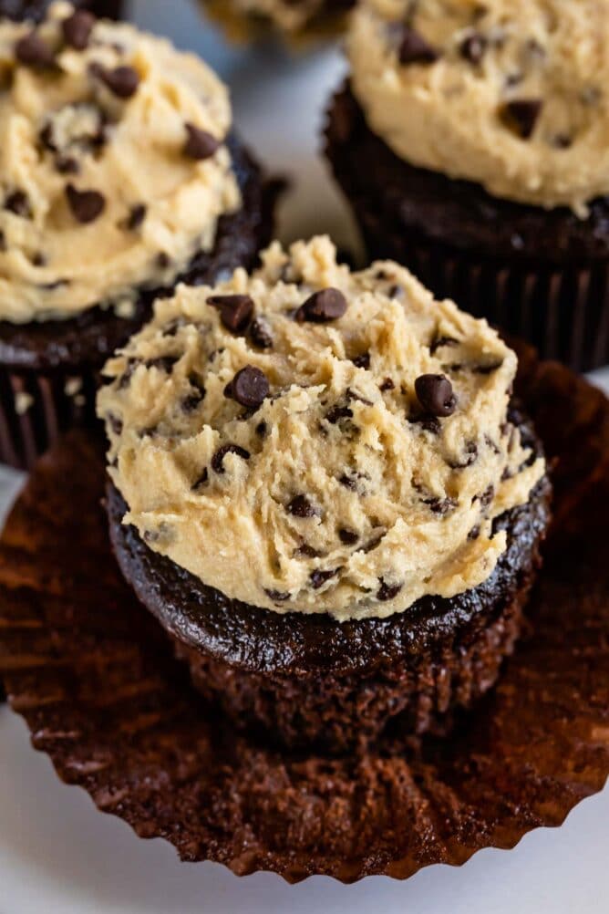 Unwrapped chocolate cupcakes with cookie dough frosting on top
