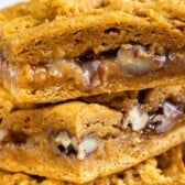 Close up shot of pumpkin gooey bars stacked on eachother with recipe title on top of image