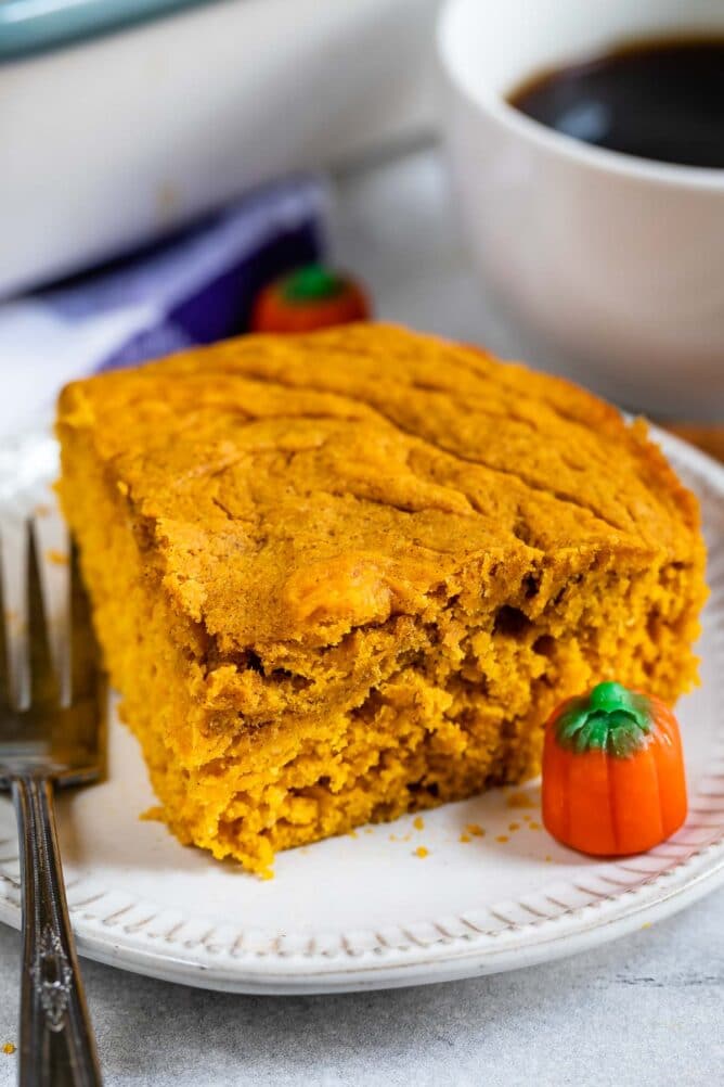 Slice of pumpkin snake cake on a plate next to pumpkin candies