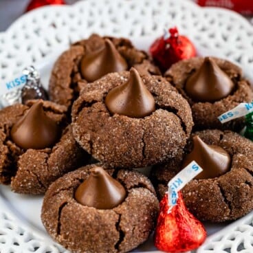 Plate full of chocolate peanut butter blossoms with Hershey kisses sprinkled on plate