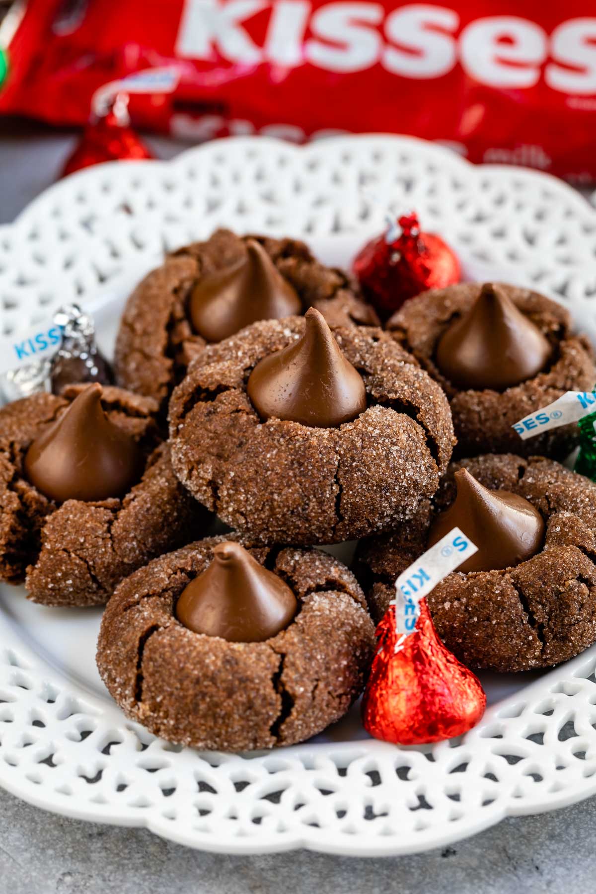 Plate full of chocolate peanut butter blossoms with Hershey kisses sprinkled on plate