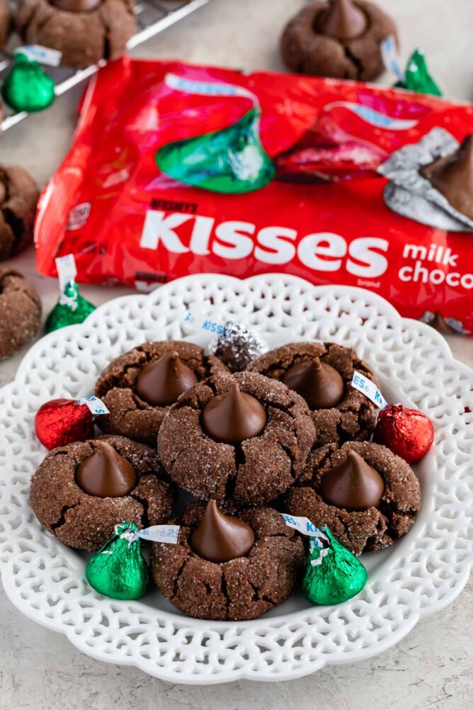 Plate full of chocolate peanut butter blossoms with Hershey kisses sprinkled on plate