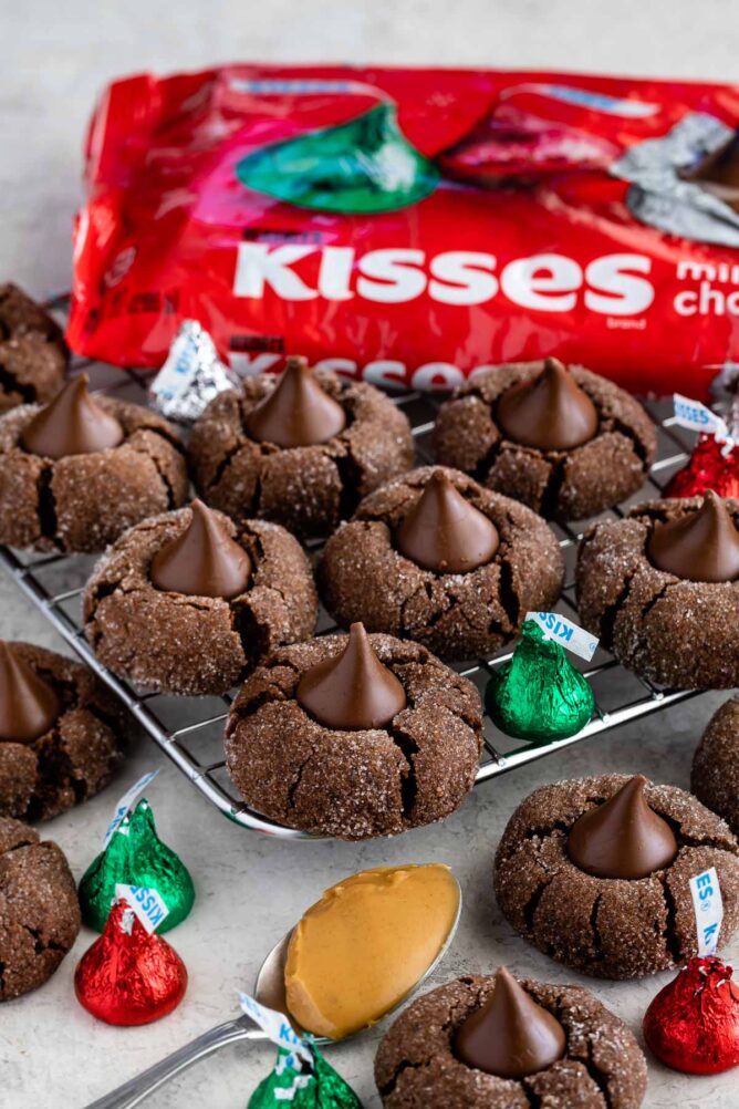 Chocolate peanut butter blossom cookies surrounded by Hershey kisses and a spoonful of peanut butter