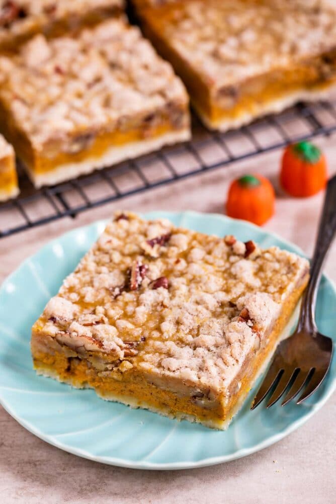 Overhead shot of pumpkin pie bar on a light blue plate with more in the background