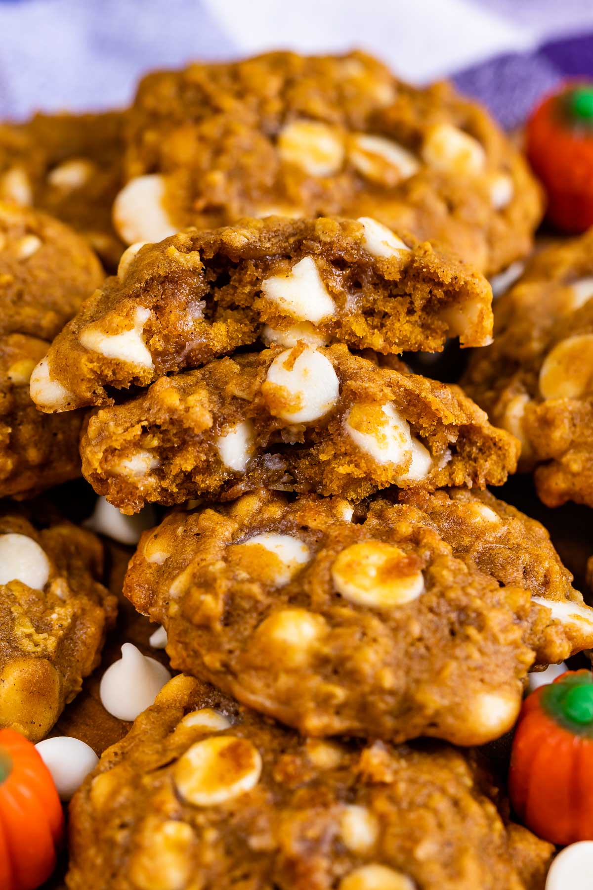 Lots of pumpkin oatmeal cookies with one split in half to show inside with white chocolate chips