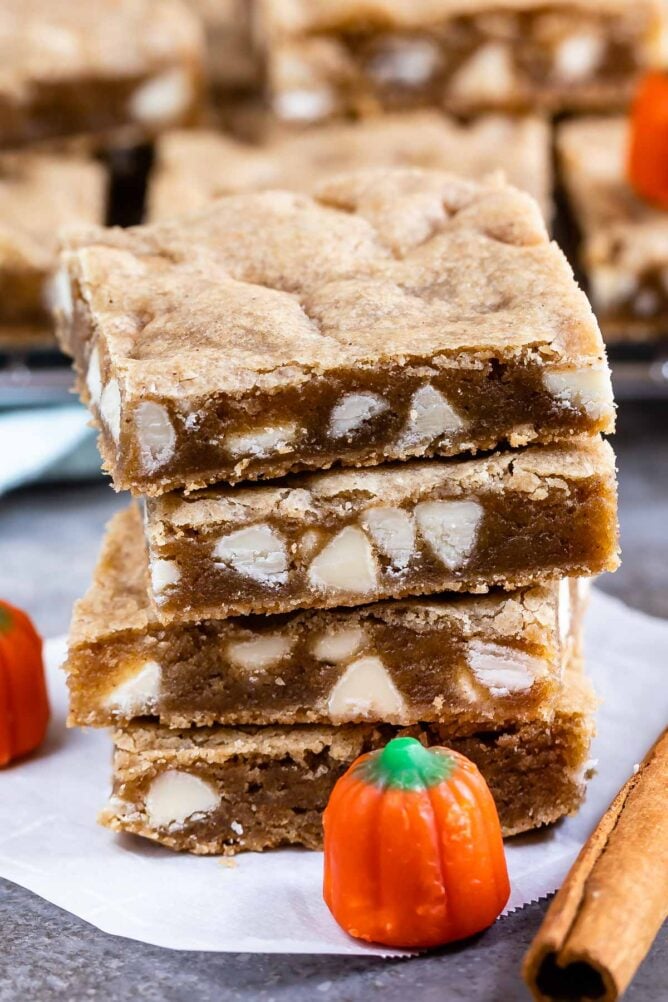 Stack of four pumpkin spice blondies with pumpkin candy and cinnamon stick