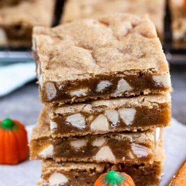 Stack of four pumpkin spice blondies with pumpkin candy and cinnamon stick