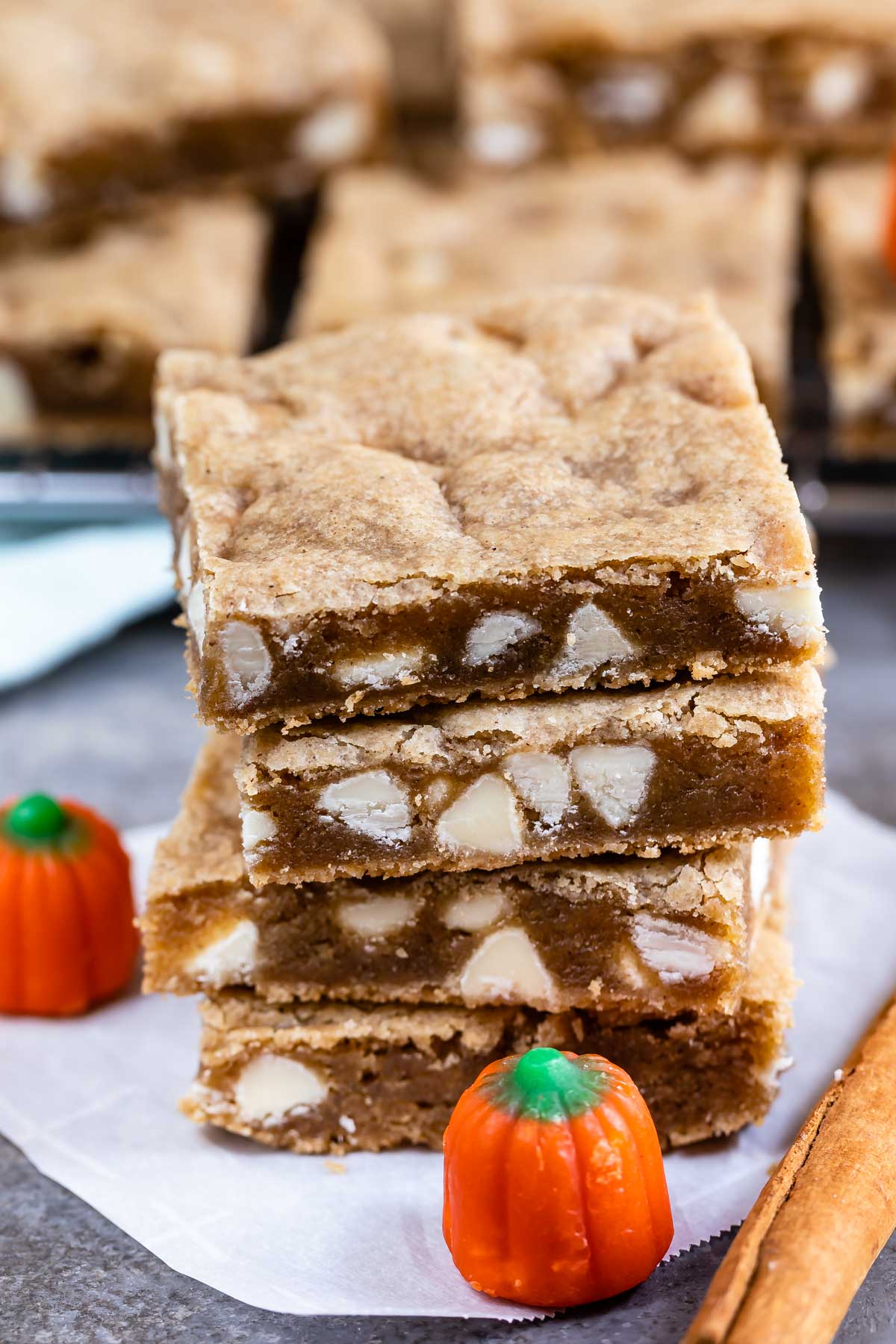 Stack of four pumpkin spice blondies with pumpkin candy and cinnamon stick