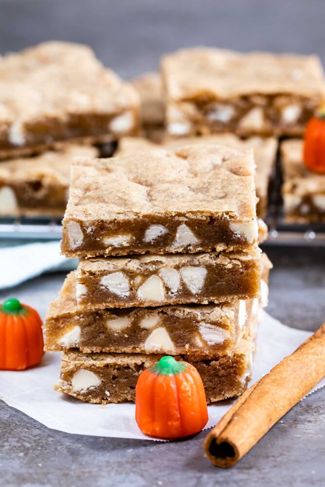 Stack of four pumpkin spice blondies with pumpkin candy and cinnamon stick
