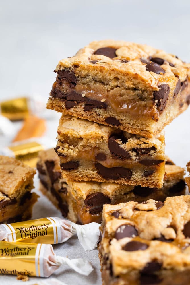 Stack of caramel chocolate chip cookie bars with candys around them