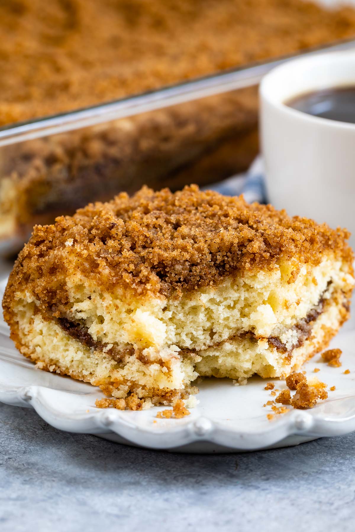 One piece of streusel coffee cake on a plate with corner piece missing