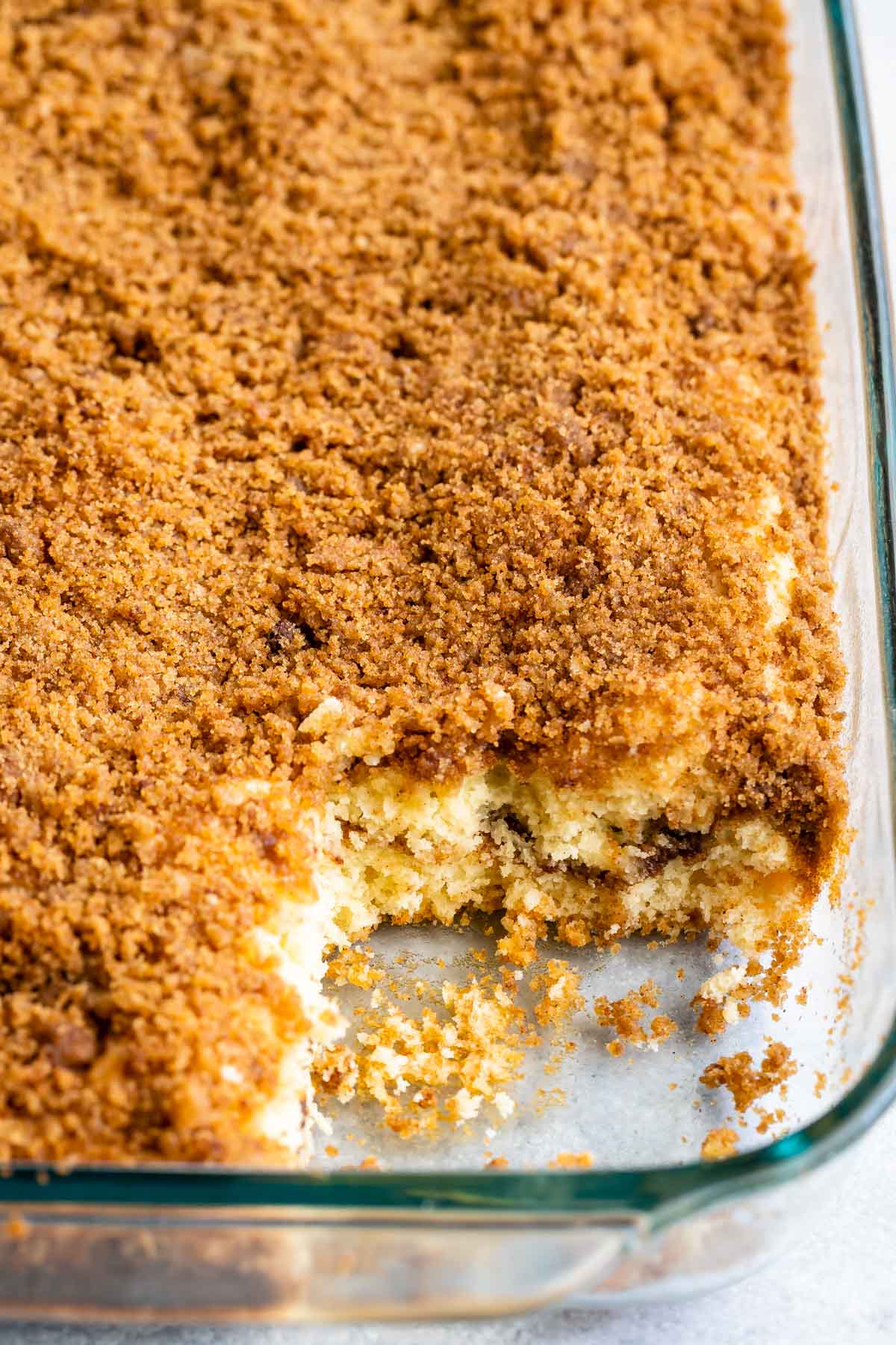 Overhead shot of streusel coffee cake in baking pan with corner piece missing