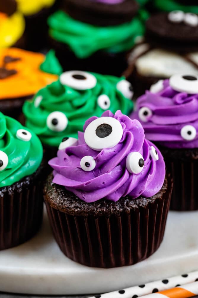 Purple and green cupcakes with googly eyes in the icing