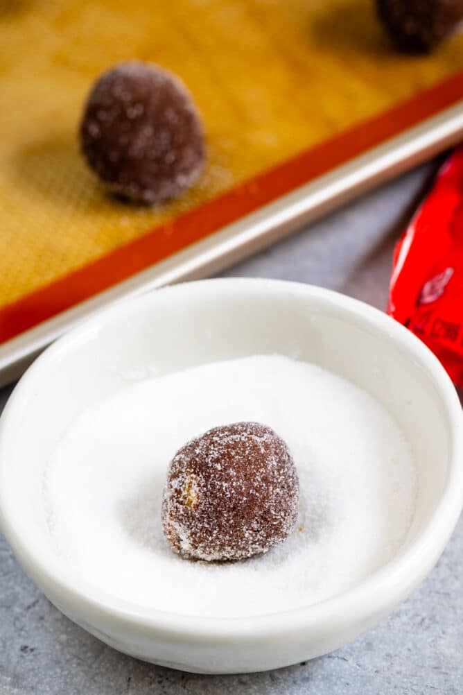 cookie dough ball in bowl of granulated sugar