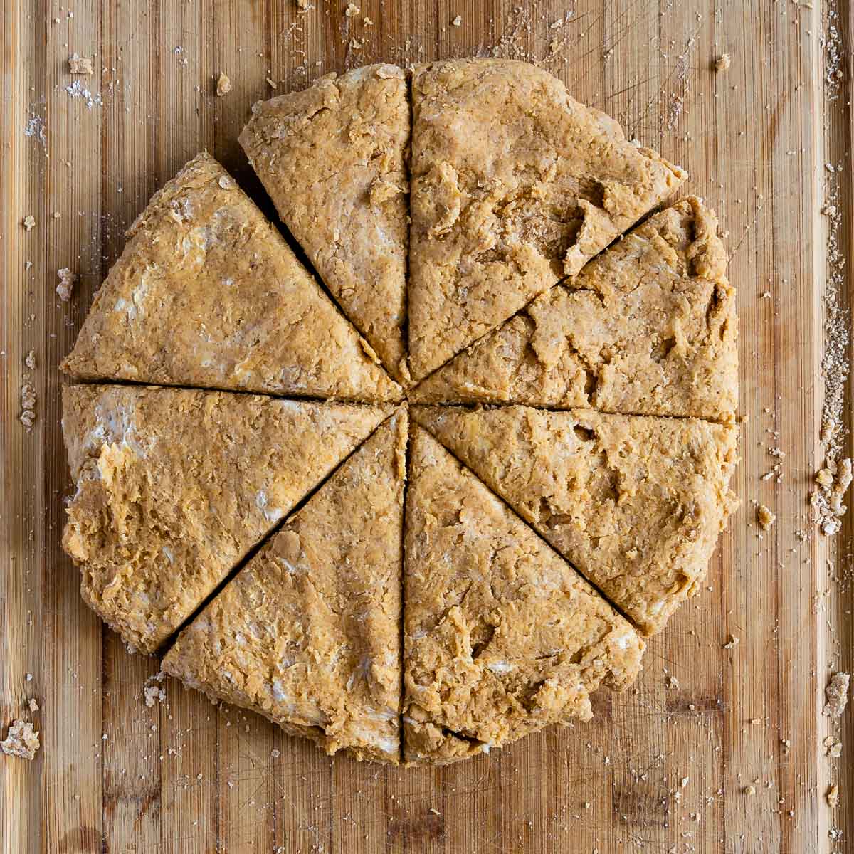 Overhead shot of pumpkin scones cut into triangles on a wooden cutting board