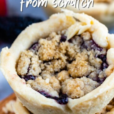 Two mini berry crumb pies stacked on top of eachother with recipe title on top of image