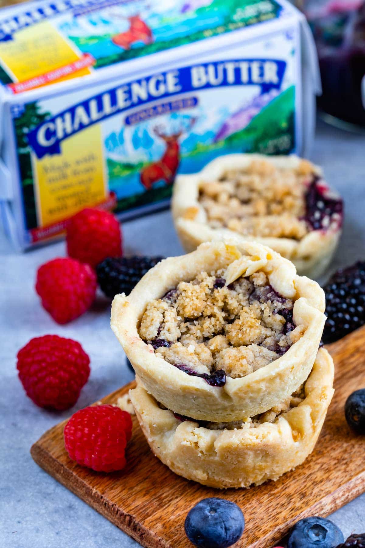 Mini berry pies with butter and fruit in the background