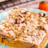 Pumpkin pie bar cut into a square on a light blue plate with recipe title on top of photo