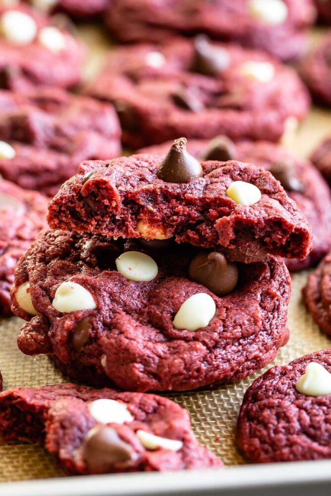 Close up shot of one red velvet cookie split in half to show inisde with more cookies all around it