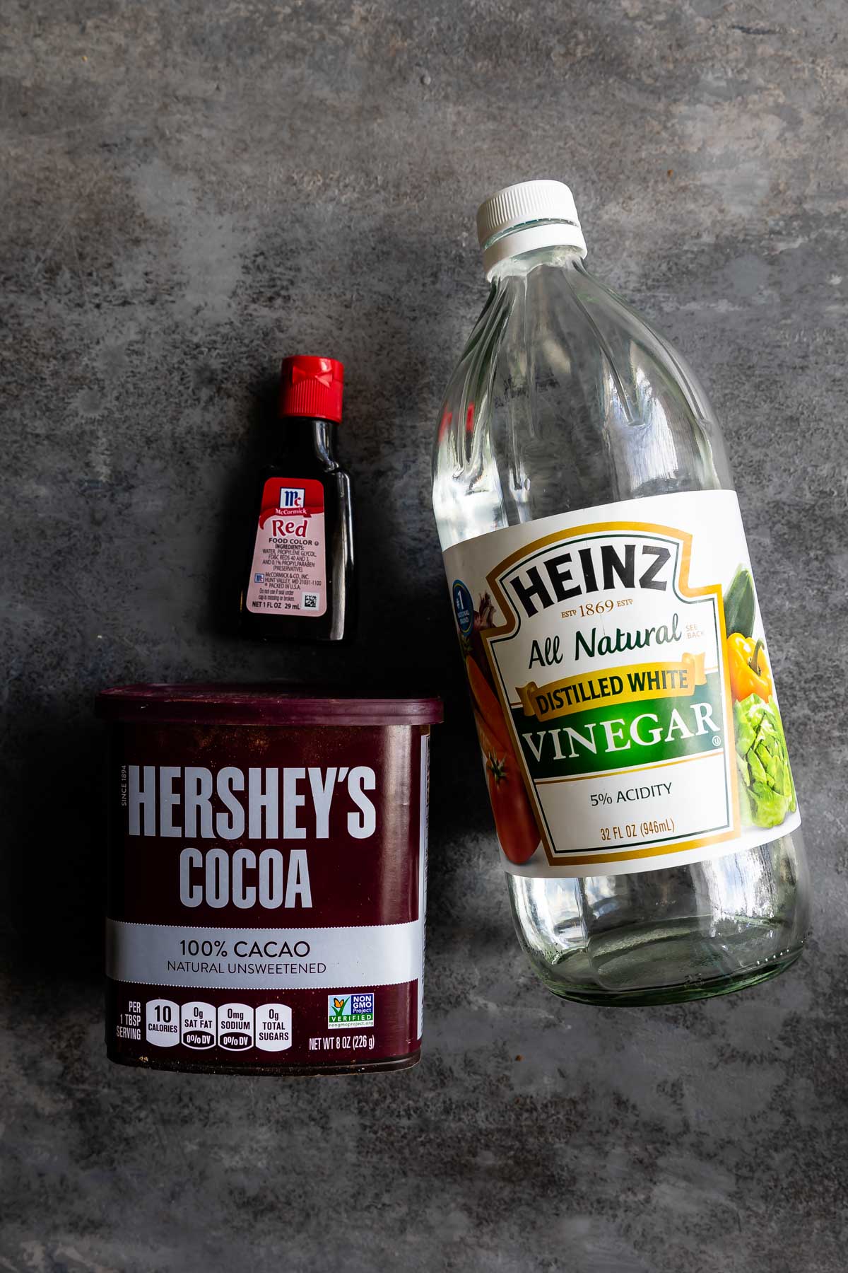 Overhead shot of red food coloring, cocoa powder and white vinegar