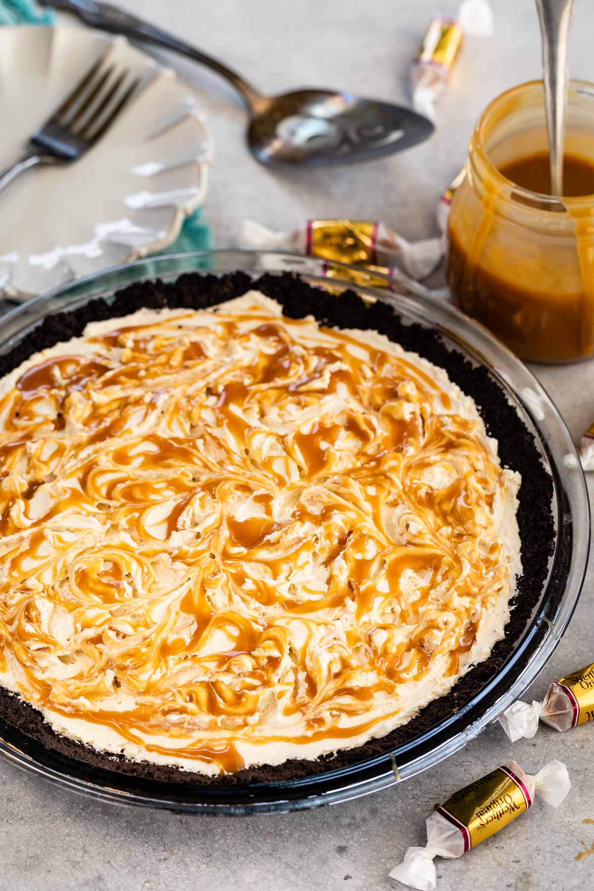 Overhead shot of caramel cheesecake pie with caramel candies and caramel sauce around it